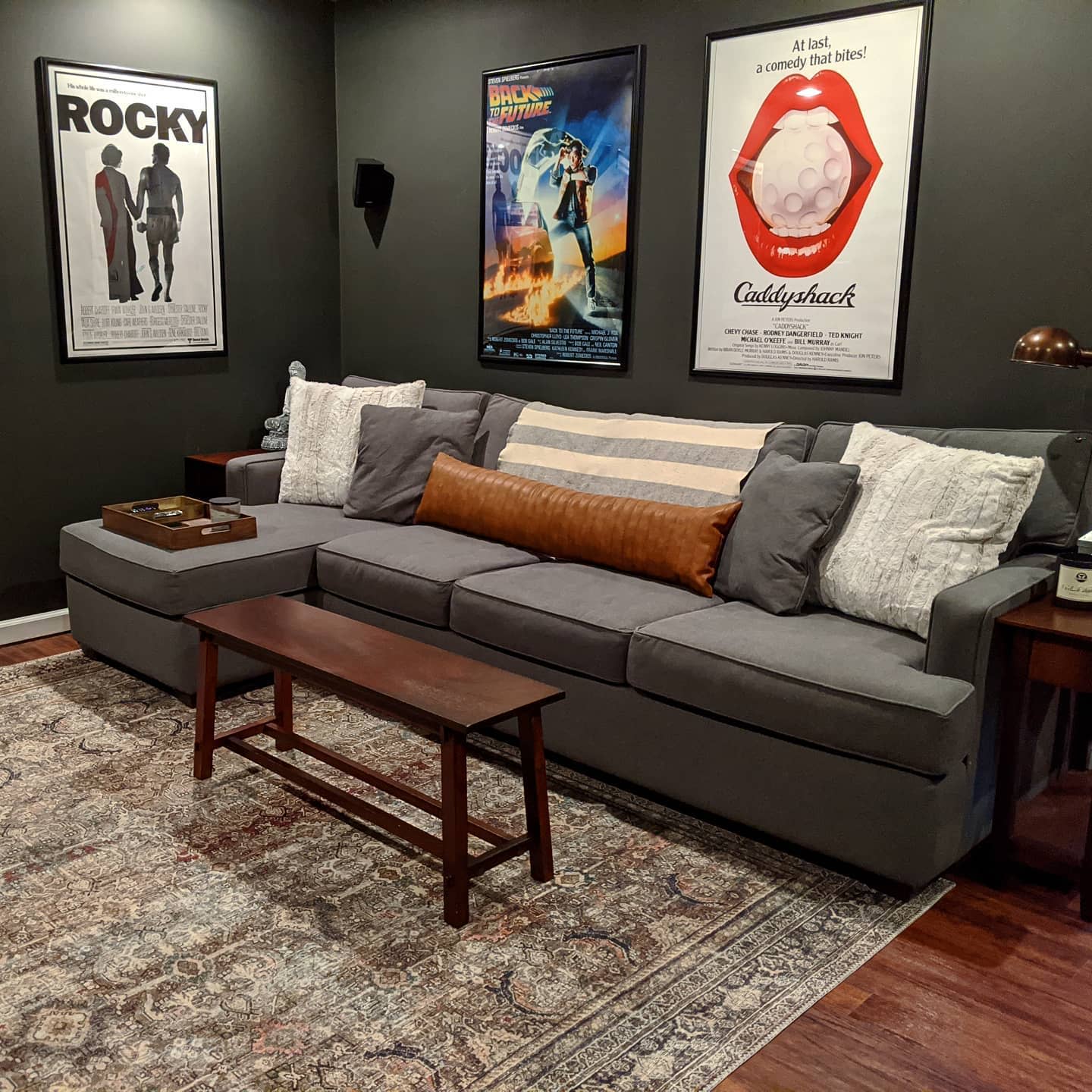 Lounge room with gray sofa, movie poster wall art, and patterned rug.
